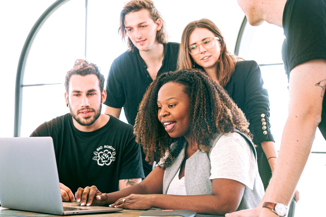 group of people using a metal laptop with a grey finish in a bright room