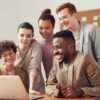 Group of people using silver metal laptop at wooden table in office