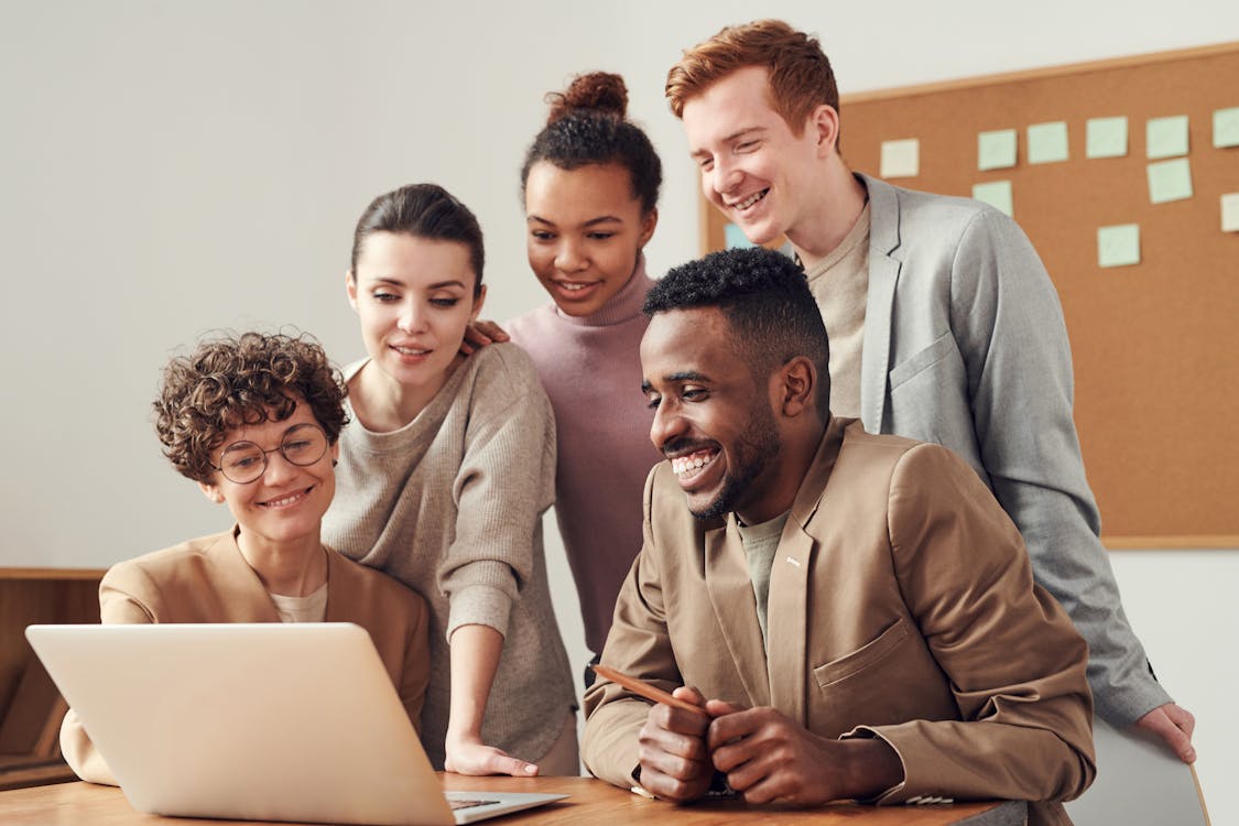 Group of people using silver metal laptop at wooden table in office