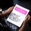 Person holding a white paper book with a black snake illustration and pink Python title