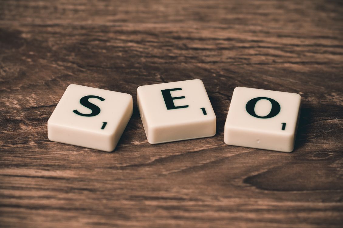 Scrabble tiles spelling SEO made of plastic on a brown wooden surface
