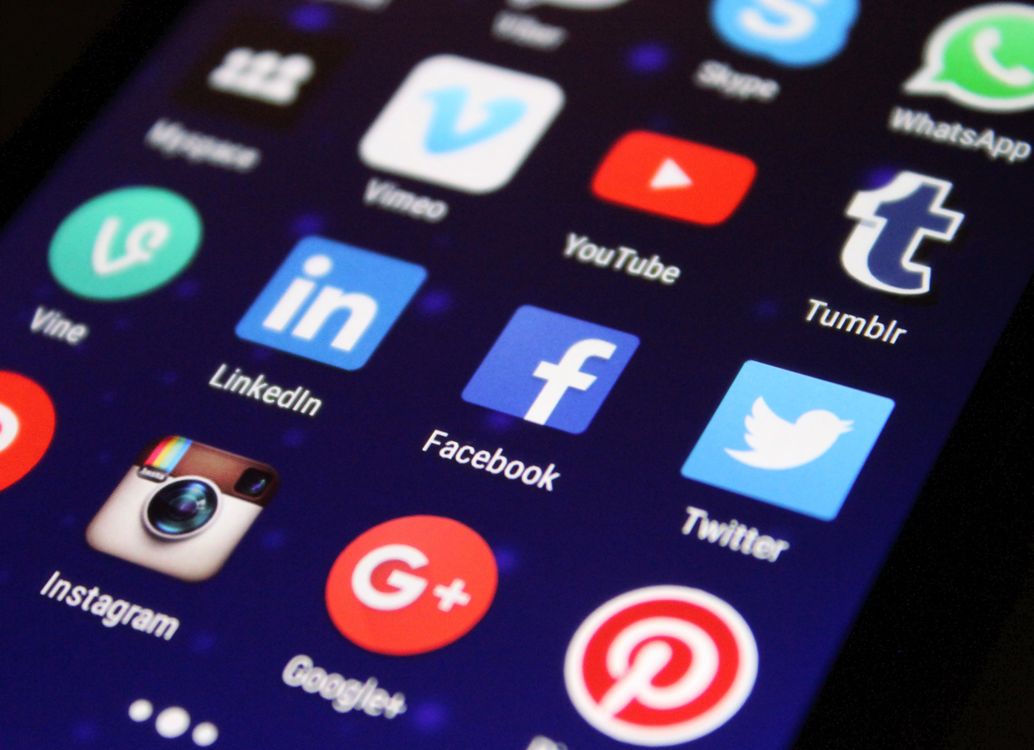 smartphone screen displaying colorful social media app icons on glass surface