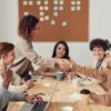 People shaking hands over a wooden table with coffee cups and laptops in a meeting room