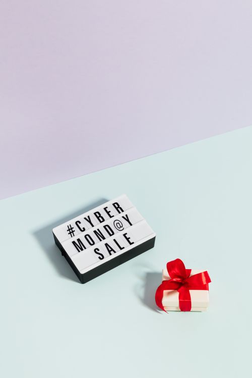 Lightbox with Cyber Monday Sale text and small gift box with red ribbon on pastel background
