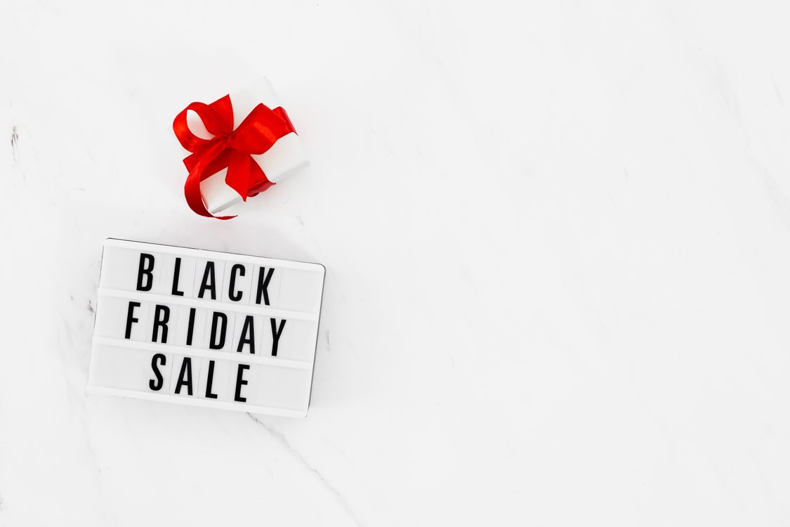 Lightbox with Black Friday Sale text and white gift box with red ribbon on white marble surface