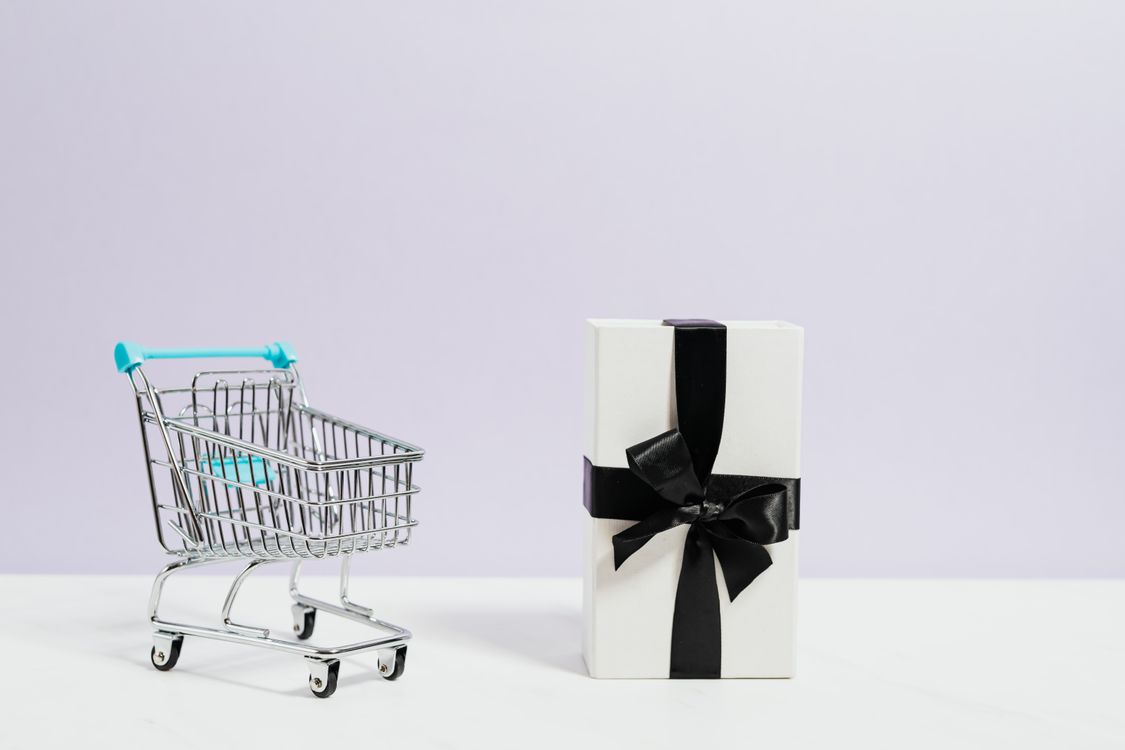 miniature metal shopping cart with blue handle and white gift box with black ribbon