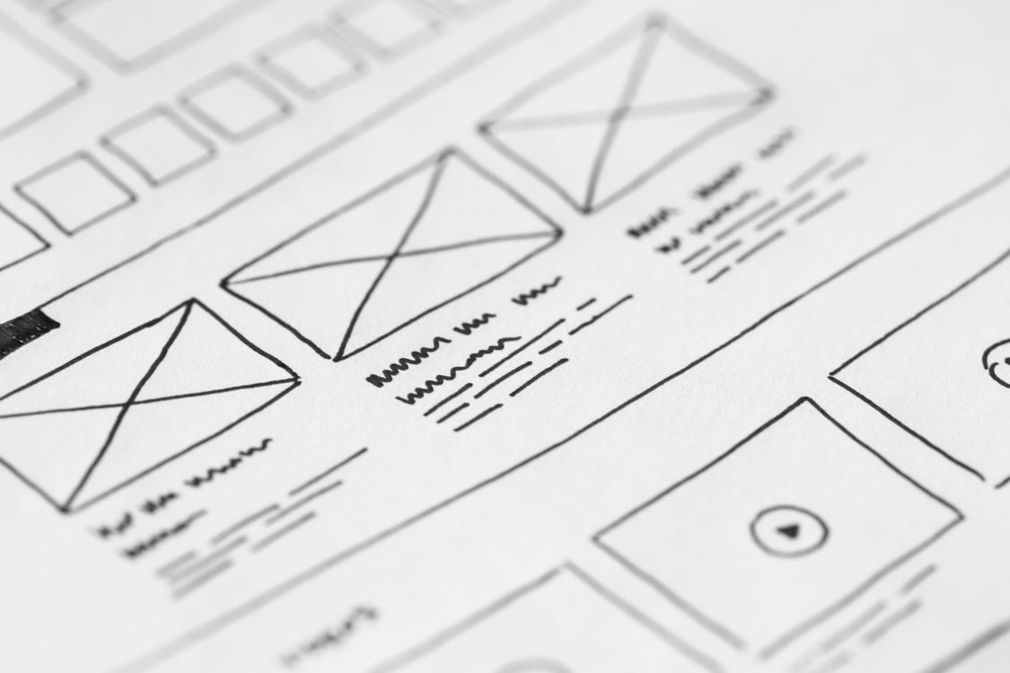 website wireframe sketches on white paper with black ink lines and text